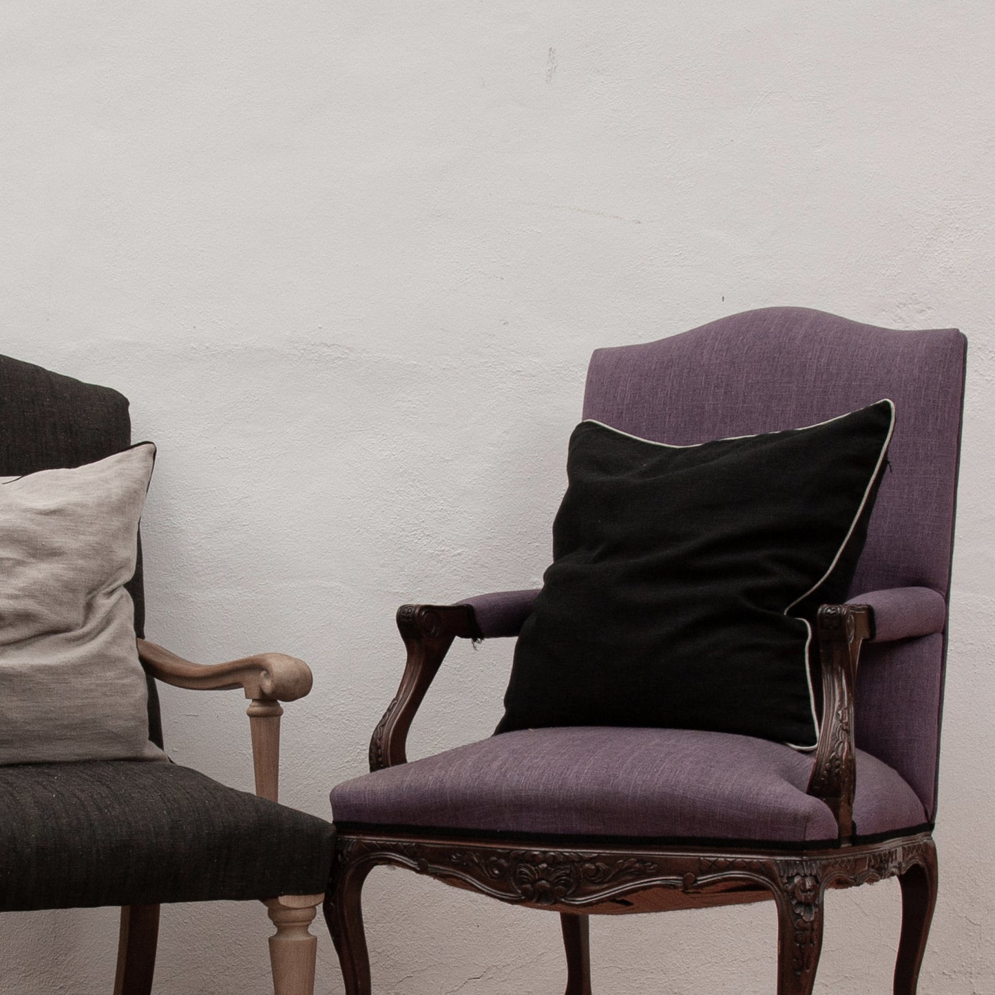 Dos cojines de lino de varios colores con bordes combinados. Ambos en sillones de lino