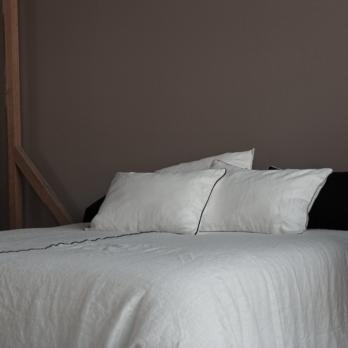 Detalle de colcha y cojines a juego de lino blanco con vivo en negro.