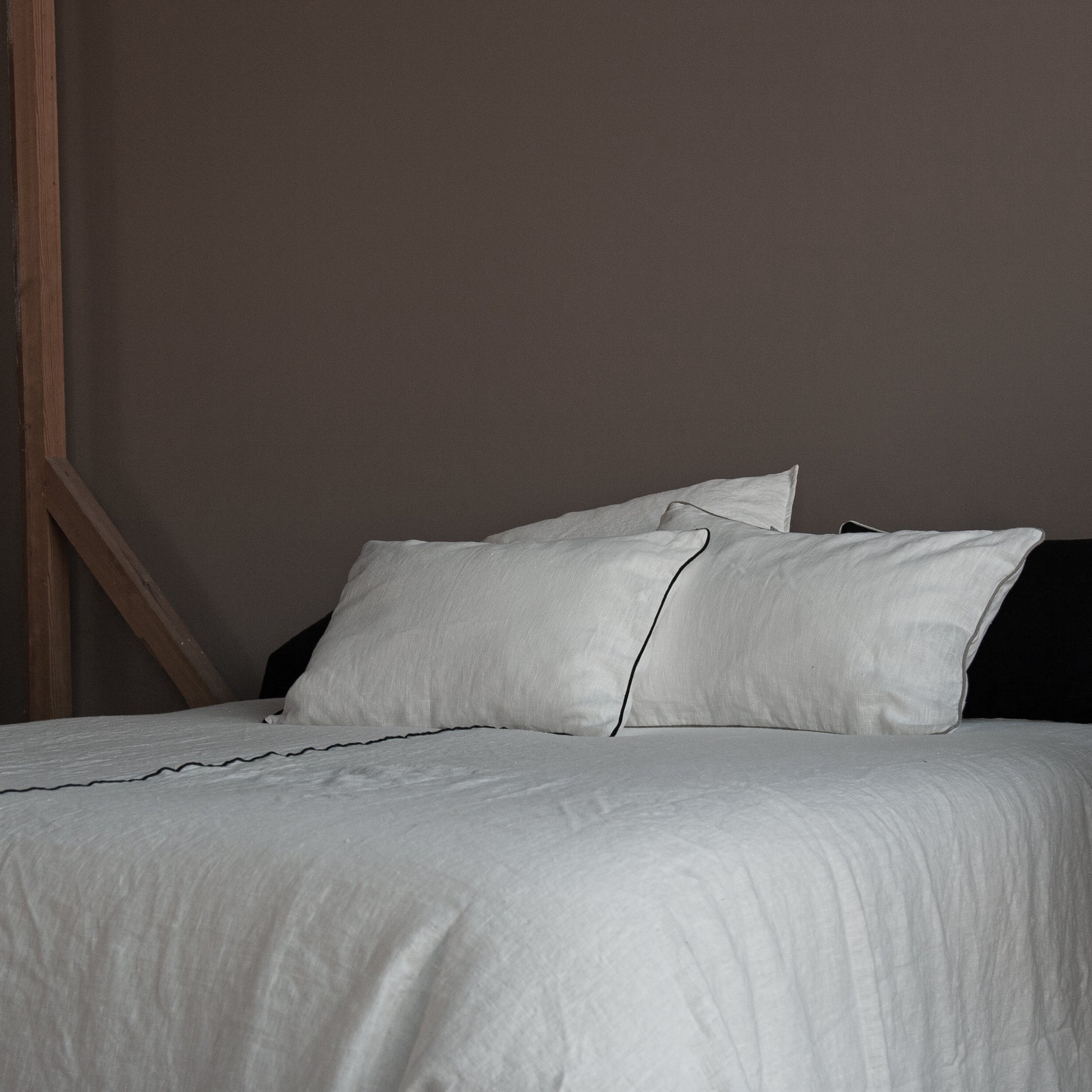 Detalle de colcha y cojines a juego de lino blanco con vivo en negro.