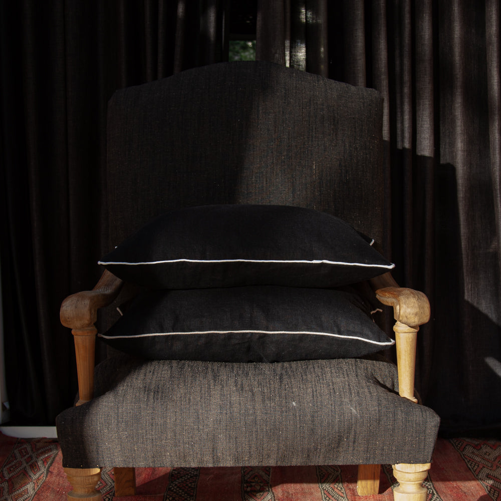 Juego de dos cojines de lino negro ribeteados en lino natural.