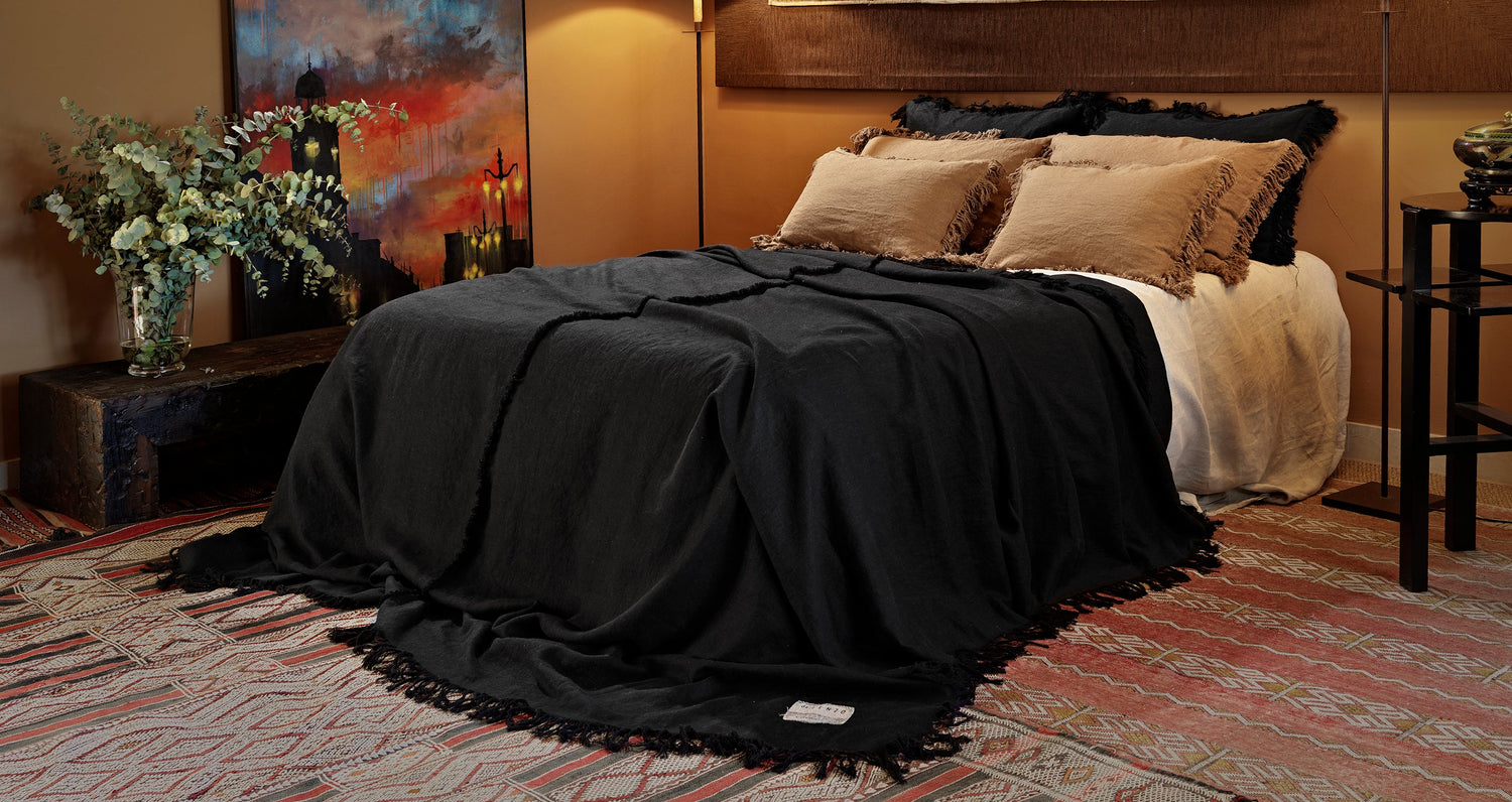Colcha negra sobre alfombras. Todo hecho a mano.