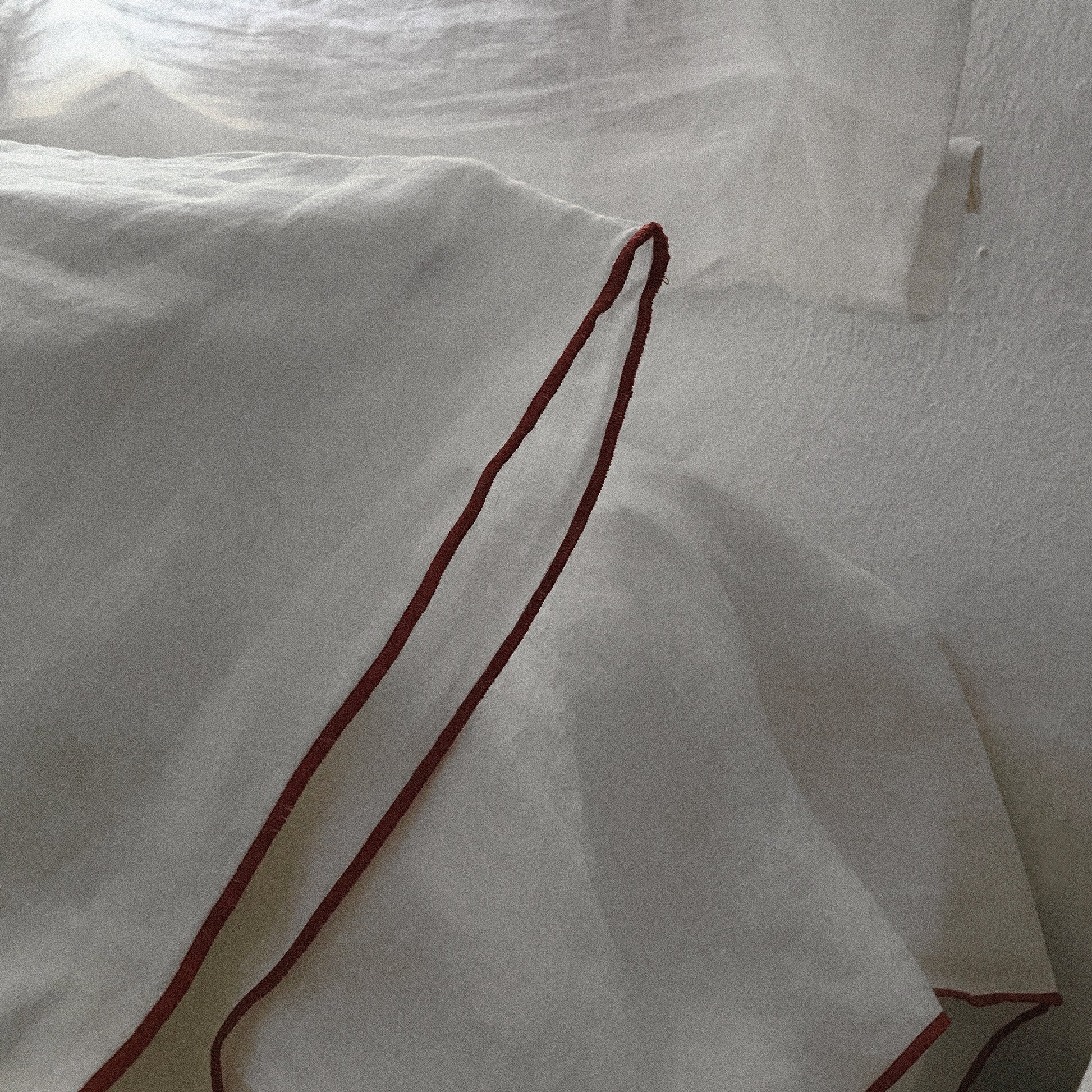 Repulgo de color burdeos en almohada de lino.