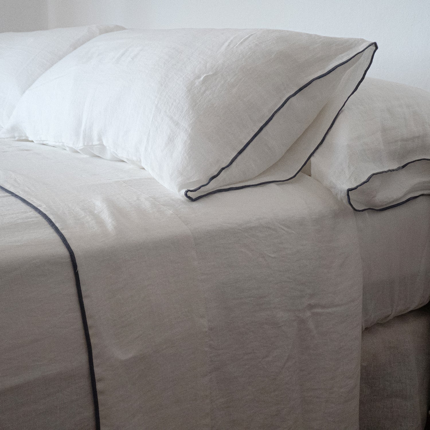 Sábanas de lino blanco con repulgo gris.