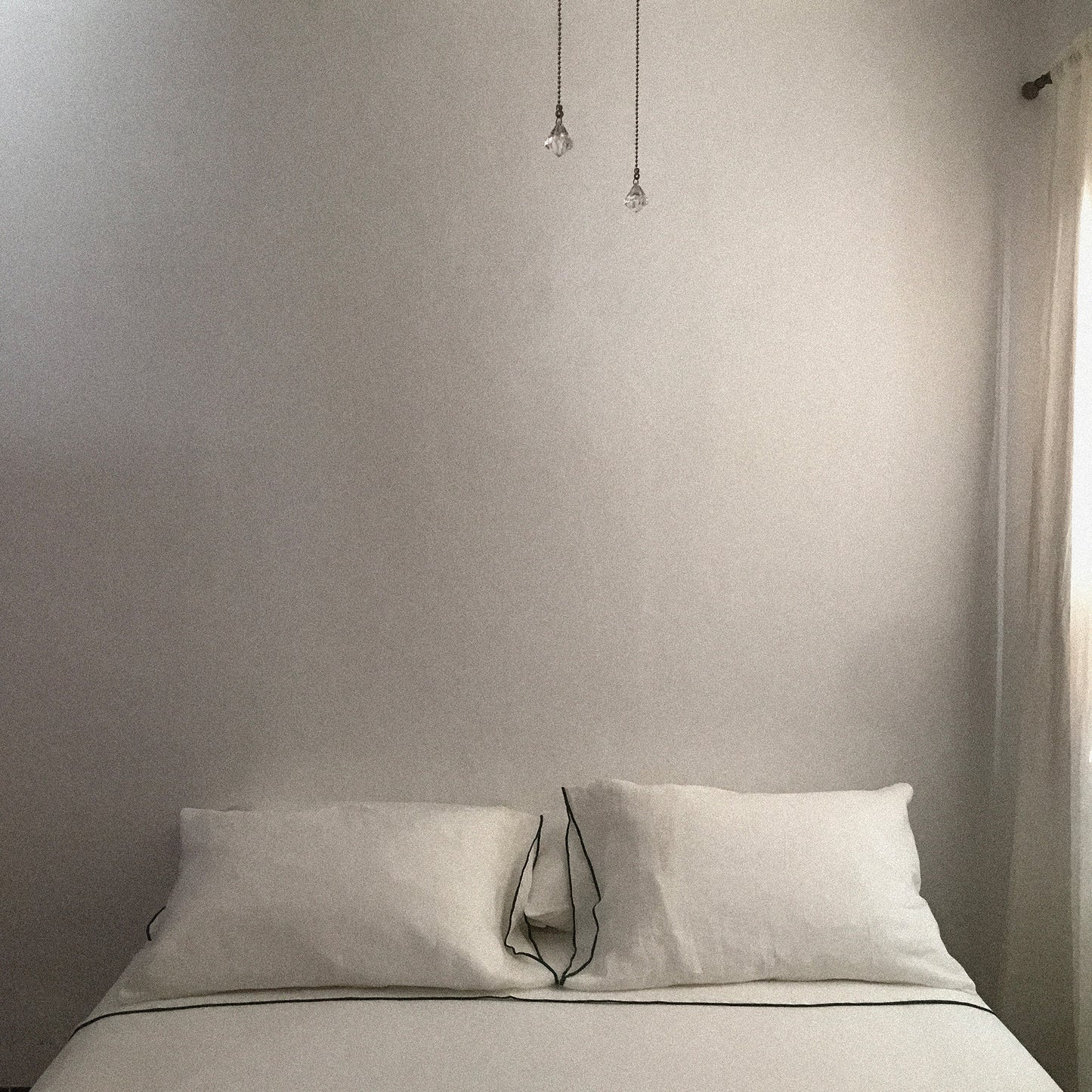 Detalle de sábanas de lino blanco en cama de matrimonio.