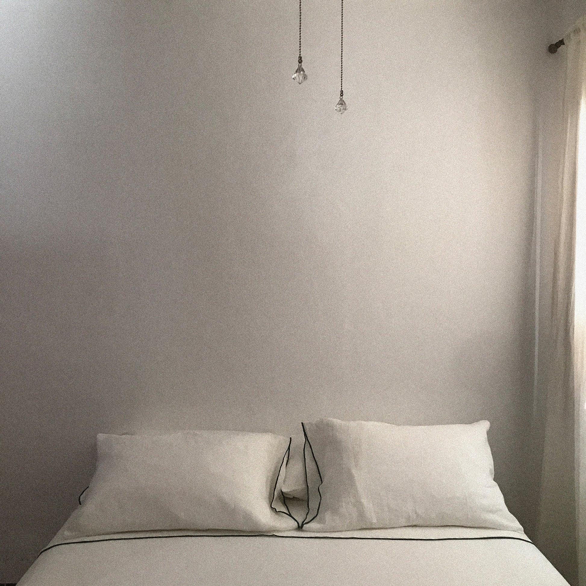 Detalle de sábanas de lino blanco en cama de matrimonio.