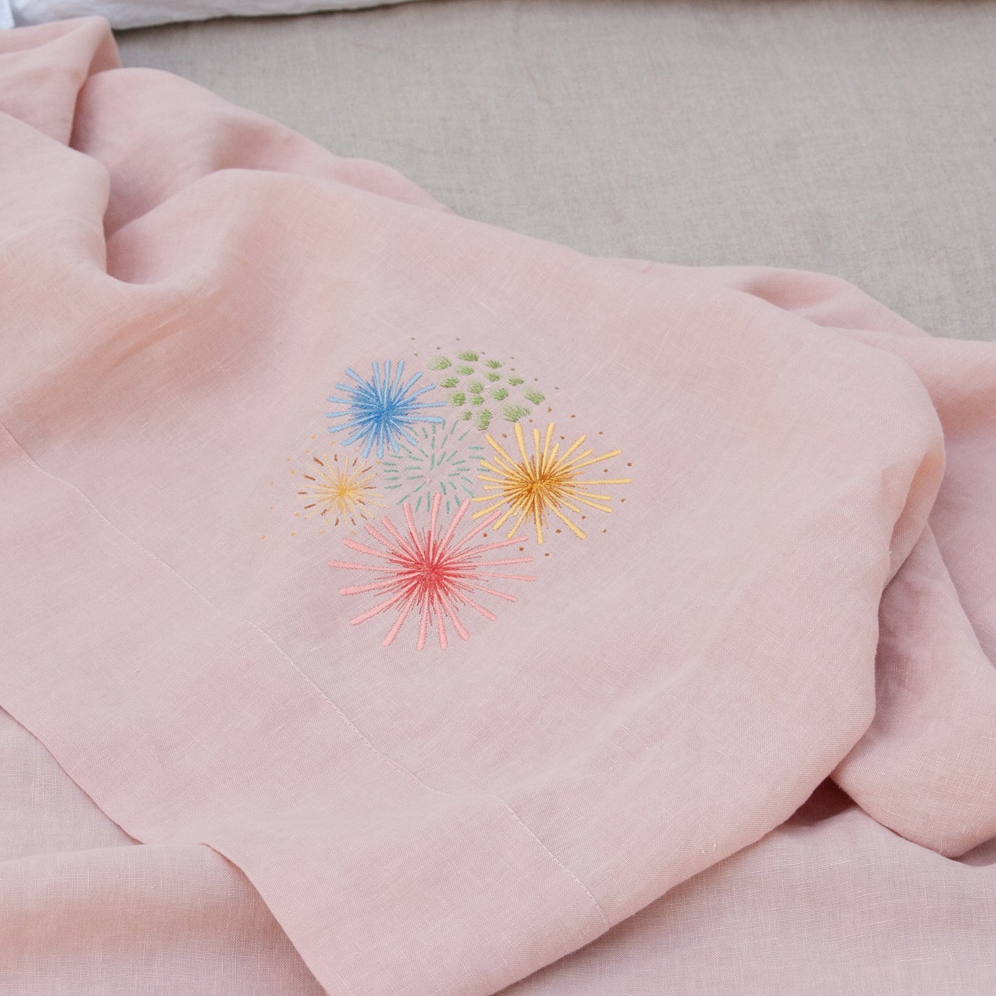 Bordados de colores sobre sábana de lino rosa.