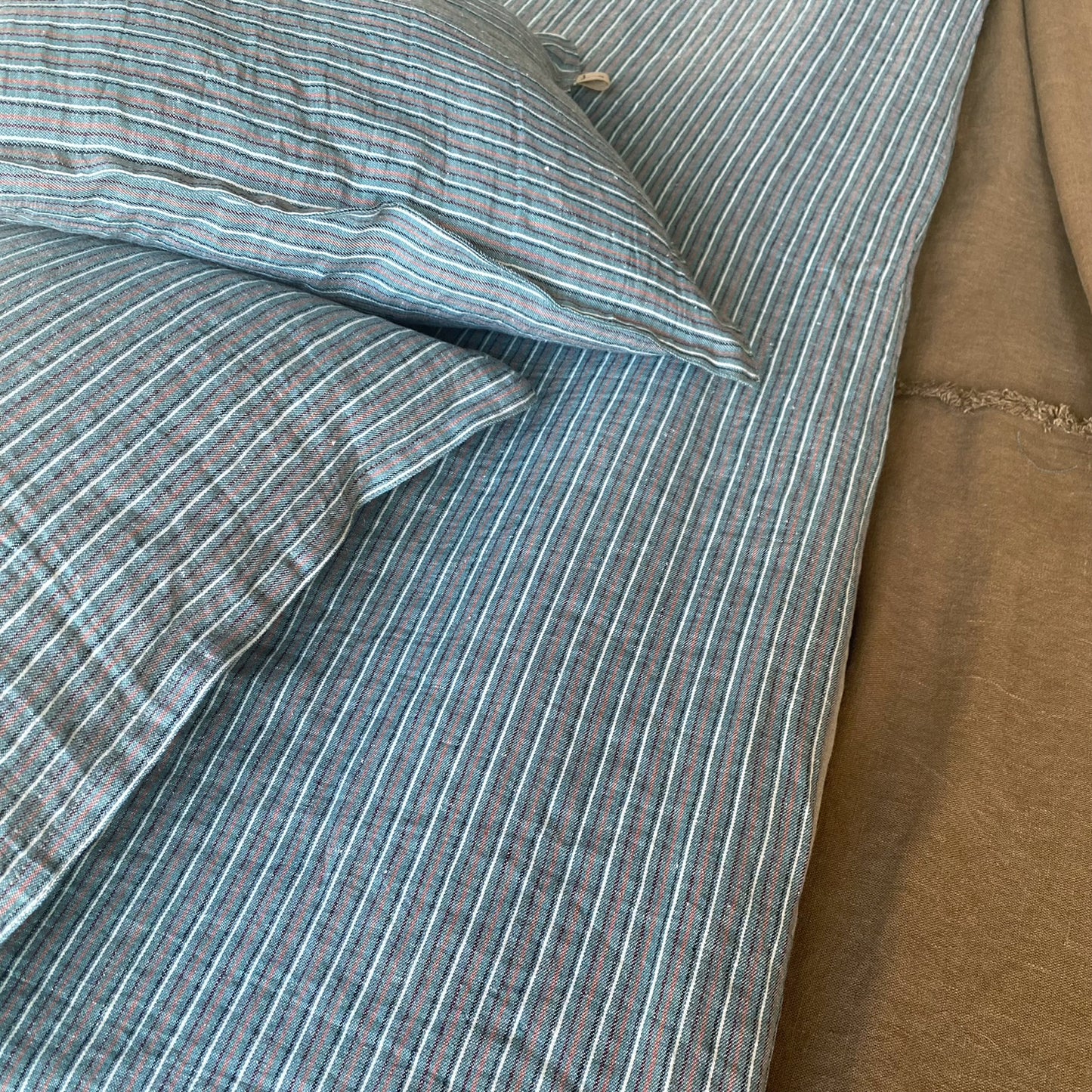 Juego de pie de cama y cojín de rayas con tonos verdes.