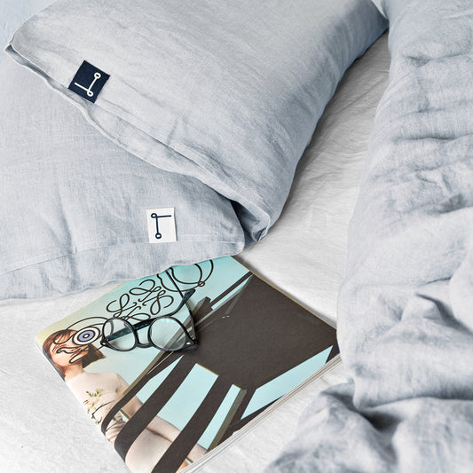 Detalle de almohadas de lino gris y bajera.