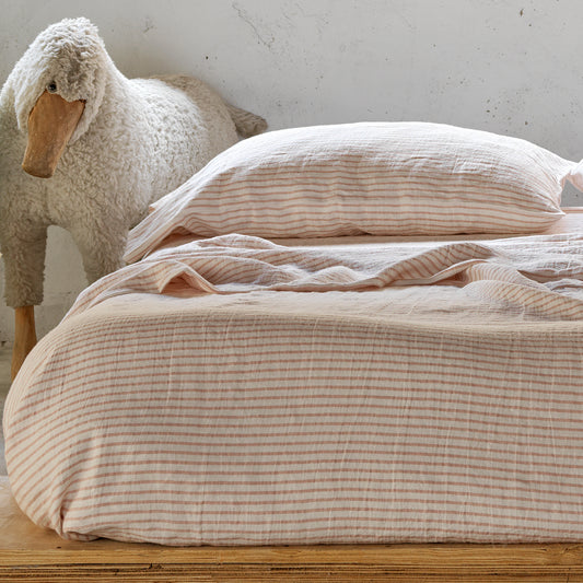 Cama de madera con amplio colchón vestido con lino rayado rosa y blanco. Lino marinero.